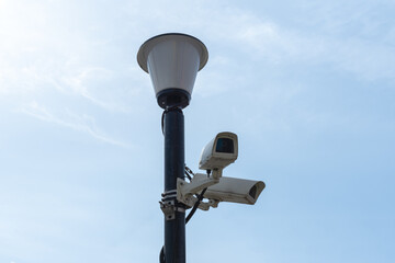 Surveillance cameras mounted on a lamp post against a blue sky. security cctv camera. Security in the city. Hidden filming of what is happening. Modern technologies and equipment