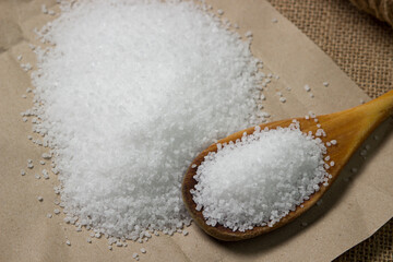 Large rock sea salt on a brown background. Wooden spoon full of salt