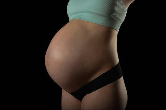 Fashion photo for pregnancy, A beautiful pregnat woman on black background, Motherhood, Big pregnant belly.