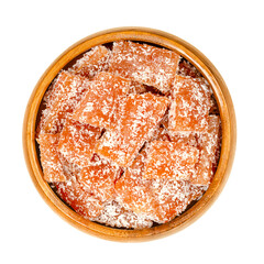 Homemade fruit jelly pieces in a wooden bowl. Sweet fruit gelee dessert with strong flavor, made of pureed fruits, such as quince, mixed with sugar and pectin. The pieces are rolled in coconut shreds.