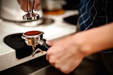 Preparing fresh coffee. Closeup of tamping Fresh Ground Coffee.