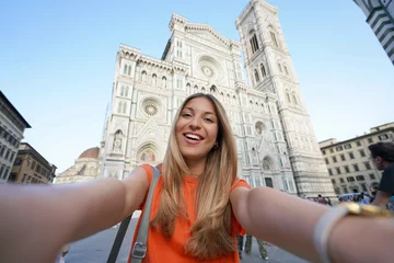Gordijnen Self portrait of beautiful traveler woman smiling at camera in front of the Cathedral on sunset in Florence, Italy © zigres