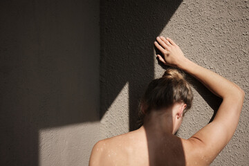 Close-up impersonal woman turn to the beige wall with bare neck, back, spine, with hand over head....