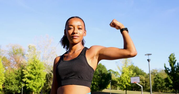 Young woman flexing muscles in park