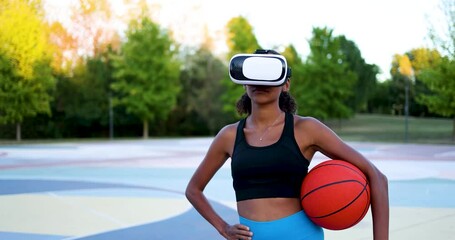 Young woman on sports court looking through VR glasses holding ball - Powered by Adobe