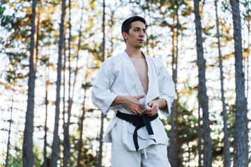 Naklejka na ściany i meble A young man doing karate in the forest training strength pose meditation 