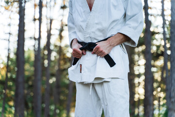 A young man doing karate in the forest training strength pose meditation 