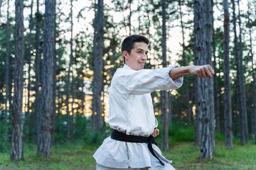 A young man doing karate in the forest training strength pose meditation 