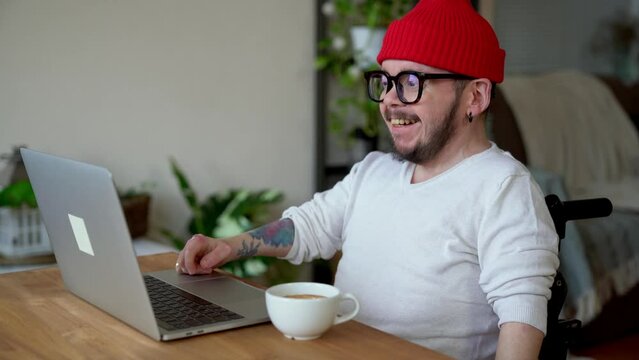 Young man with disability wearing red cap talking in video conference