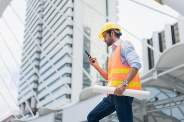 Man engineer standing on construction site. construction manager using walkie talkie. Engineer working on outdoor project and talking on phone