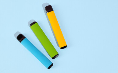 Set of colorful disposable electronic cigarettes on a blue background. The concept of modern smoking. Top view