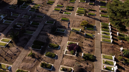 Woman and man praying in front of grave during sunny day at cemetery in Buenos Aires