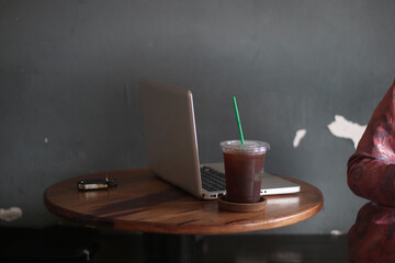 A cup of amaricano and laptop on the wood table