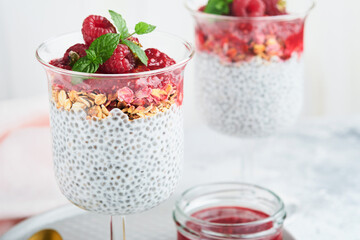 Chia pudding. Healthy vanilla chia pudding in glass with fresh raspberries and mint on white background. Vegan healthy breakfast.