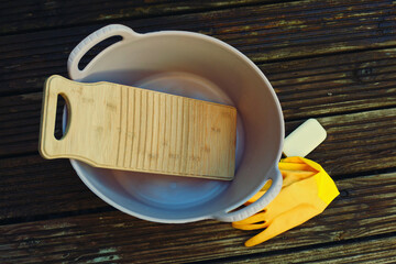 a bamboo laundry board in a rubber tub with a piece of soap and a pair of rubber gloves - 537035408