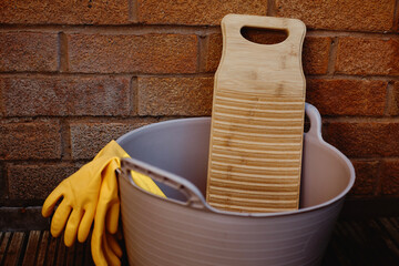 a bamboo laundry board in a rubber tub against a brick wall - 537035452