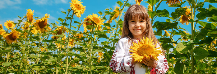 A child in a field of sunflowers in an embroidered shirt. Ukrainian. Selective focus.