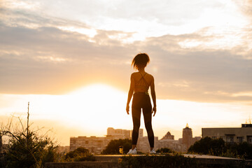 Black runner woman standing in summer park on sunrise
