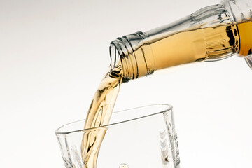 pouring bourbon whiskey into a glass from the neck of a bottle close-up white background