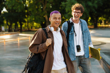 Two young handsome smiling stylish friends looking at camera