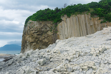 Columnar basalt rock, Cape Stolbchaty on Kunashir Island, in the foreground bases of lava basalt...