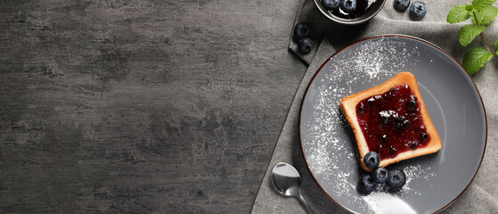 Delicious toast served with jam and blueberries on grey wooden table, flat lay with space for text. Banner design