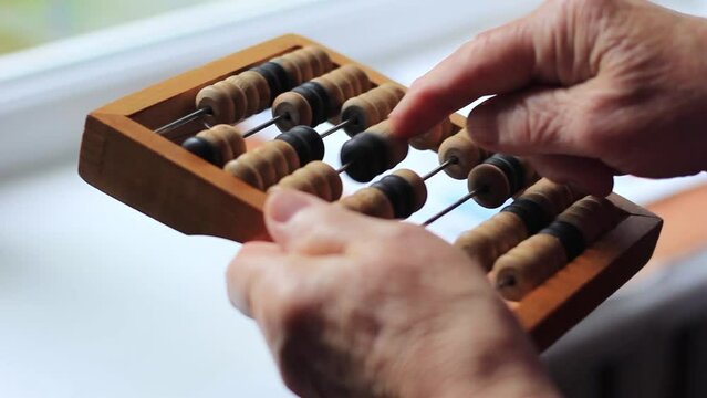old woman's hand counts on vintage abacus