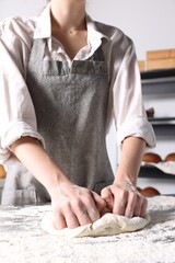 Obraz na płótnie Canvas Woman kneading dough at table in kitchen, closeup