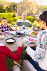 Vertical picture of caucasian family spending time together outside and praying before meal
