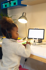 Vertical picture of happy african american girl learning, using tablet at home