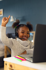 Vertical picture of happy african american girl learning, using tablet at home
