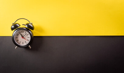 Top view of black alarm clock on yellow and black background. Shopping concept boxing day and Black...