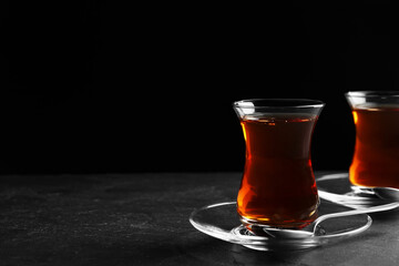 Glasses with traditional Turkish tea on black table, space for text
