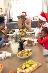 Vertical picture of african american family praying before having christmas meal