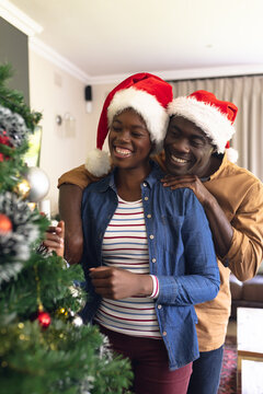Vertical picture of african american couple spending time together and decorating christmas tree