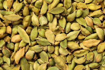 Pile of dry green cardamom pods as background, top view