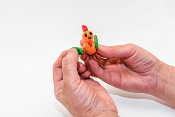 A woman sculpts a cockerel out of plasticine. Master class on making handmade crafts