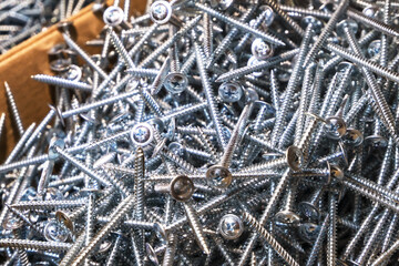 A lot of metal screws close-up in bulk.