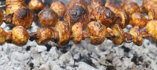 Potatoes with pieces of lard on a grill with coals