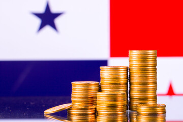 A stack of gold coins on the background of the flag of 
Panama. Country economy concept