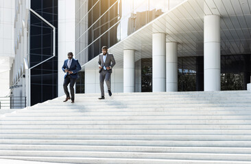 Business people walk down the stairs to a modern glass building. Work in a large company. Career growth and advancement. Increasing and improving skills. Salary increase