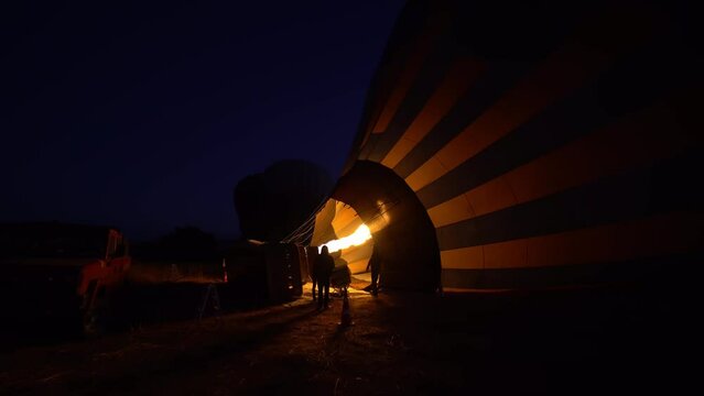 Close-up of balloon at night as it inflates for flight, burning burner fire to lift balloon into air Cappadocia, turkey. Park in Goreme where people gather for photos with balloons.