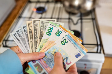 Euro and dollar banknotes on the background of a burning gas burner. Concept of increasing cost of...