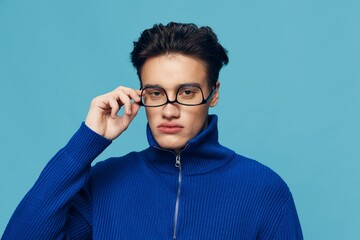 a handsome, attractive man stands on a light blue background in a blue zip-up sweater with...