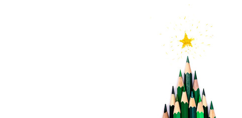 A creative Christmas tree made of green pencils on a white background, a yellow star made of shavings on the top.Christmas and New Year flat lay.