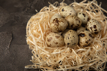 Naklejka na ściany i meble Quail eggs in a nest on a black texture background. Whole and broken quail eggs. Natural products. Place for text. Fresh quail eggs. Protein. Calcium.