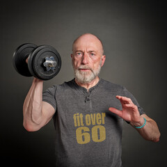 bald and bearded man wearing t-shirt with the added over 60 text is exercising with a heavy...