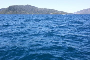 View from deep water surface to blue sea with mountain islands. Background for travel and vacation