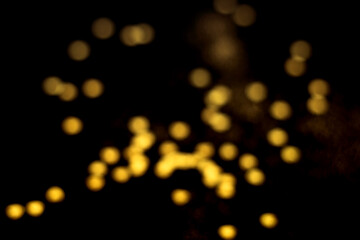 Obraz premium Golden blurred bokeh lights on black background. Glitter sparkle stars for celebrate. Overlay for your design