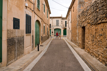 Fototapeta na wymiar Two travelers in the Beautiful streets in a picturesque village in Santanyi, Majorca, Spain